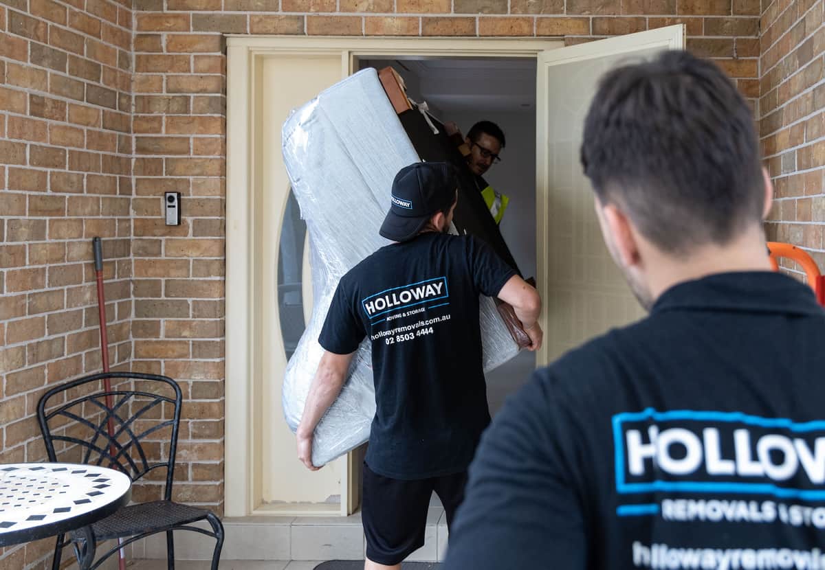 Removalists moving furniture in a house