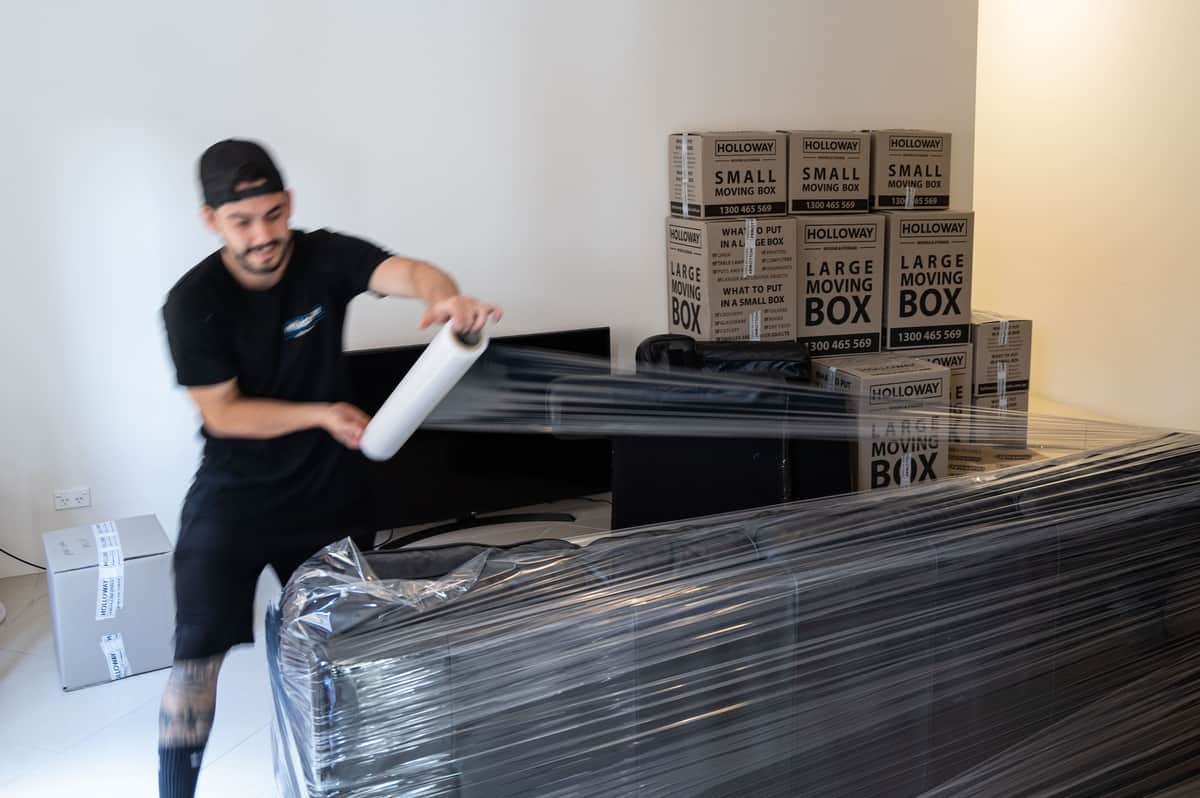Removalists wrapping furniture with protective materials