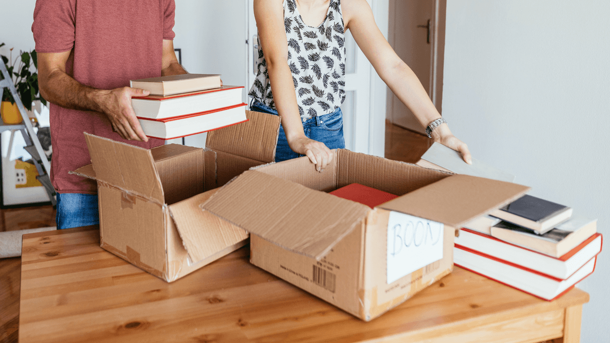 couple packing books for moving in small boxes