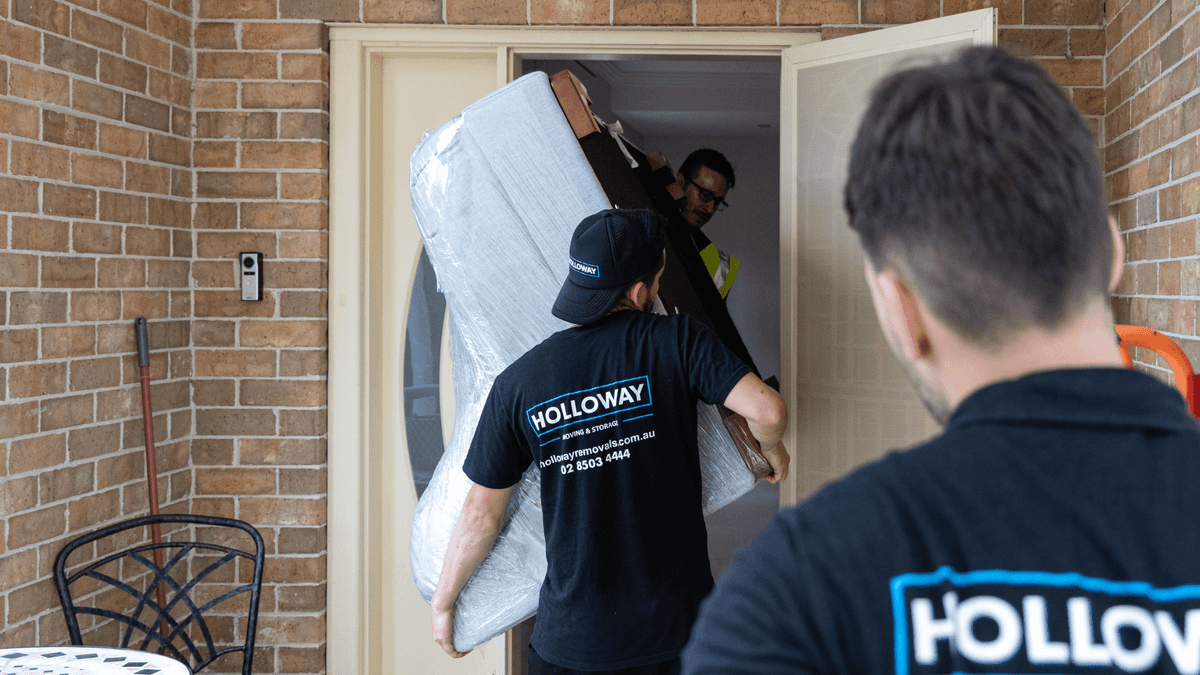 Two Holloway removalists carrying wrapped furniture during Melbourne home move