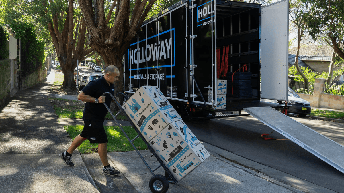 removalists using trolley to move boxes into moving truck