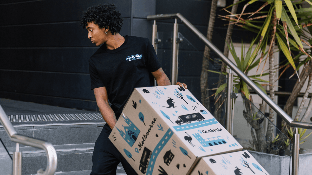 holloway removals removalist pulling a trolley of moving boxes up apartment stairs