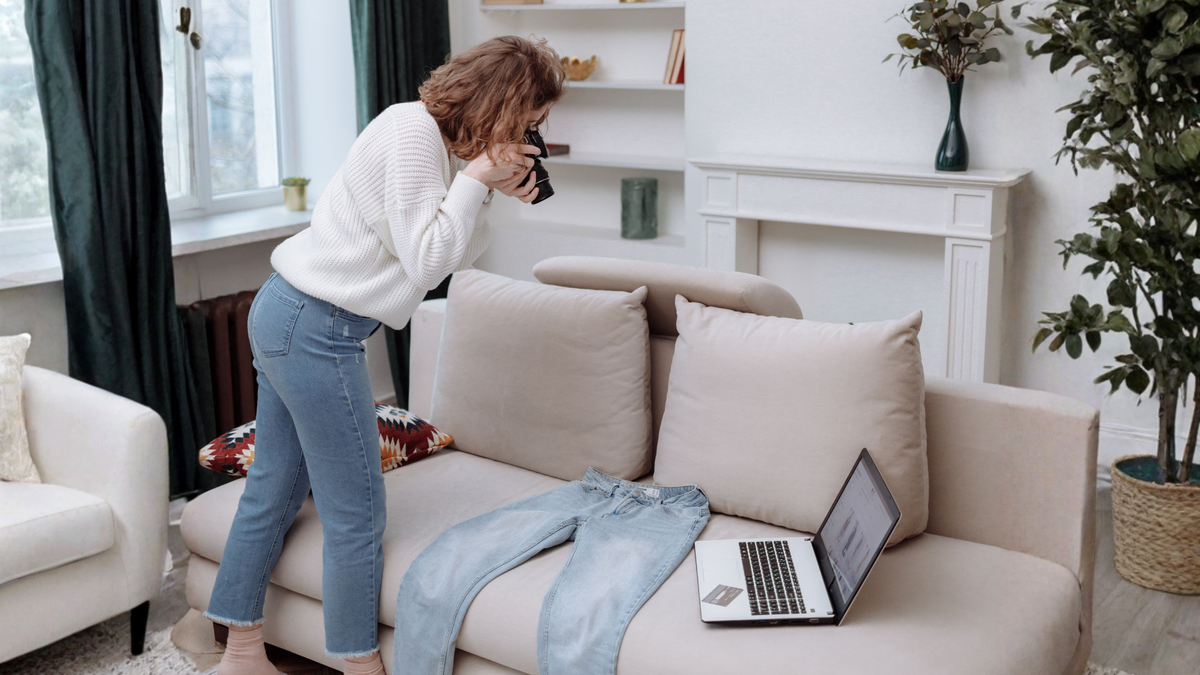 Woman photographing sofa to sell online before moving house