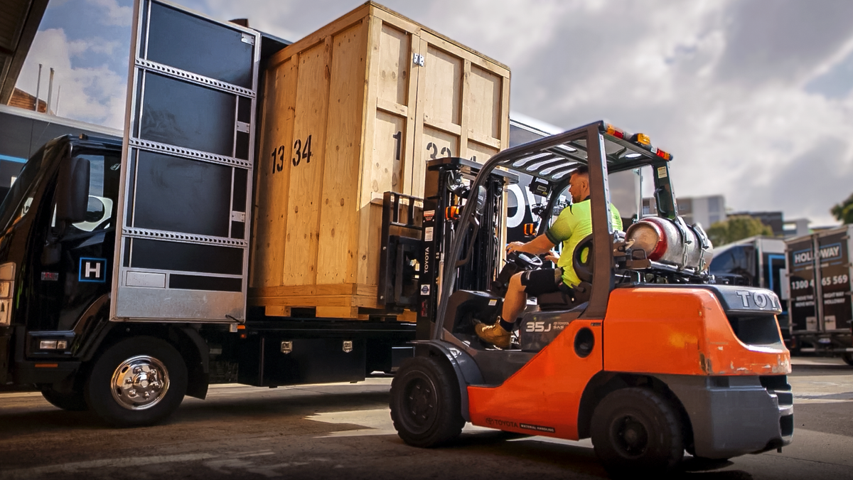 Holloway Storage worker on a forklift loads a storage module onto a truck