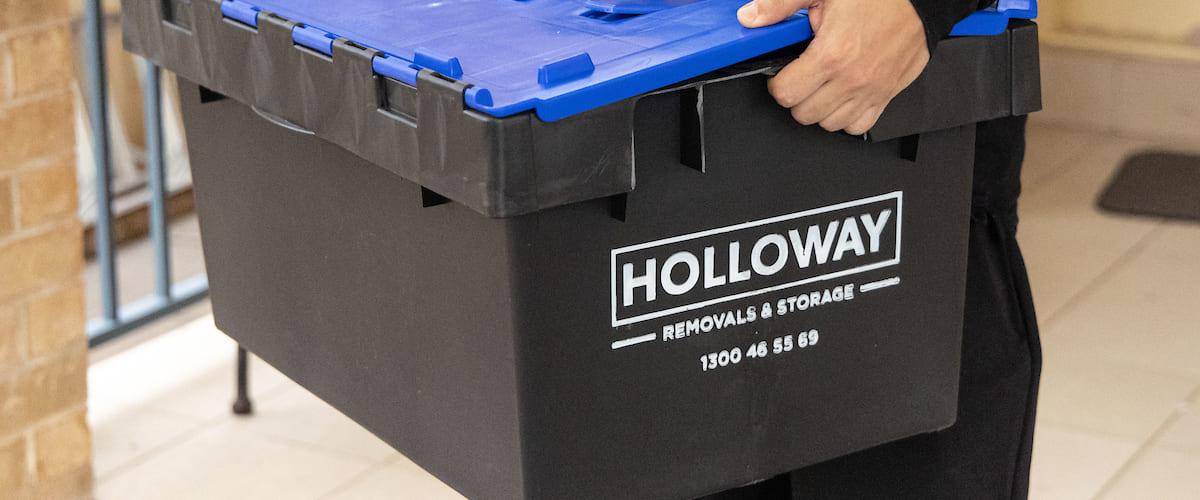 close up of someone holding a plastic holloway removals storage box